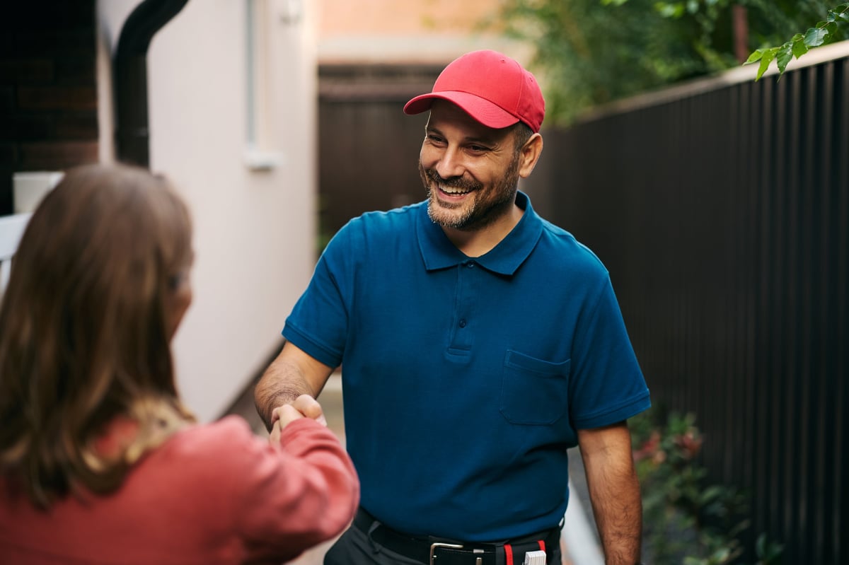 Happy handyman handshaking with his customer in the backyard